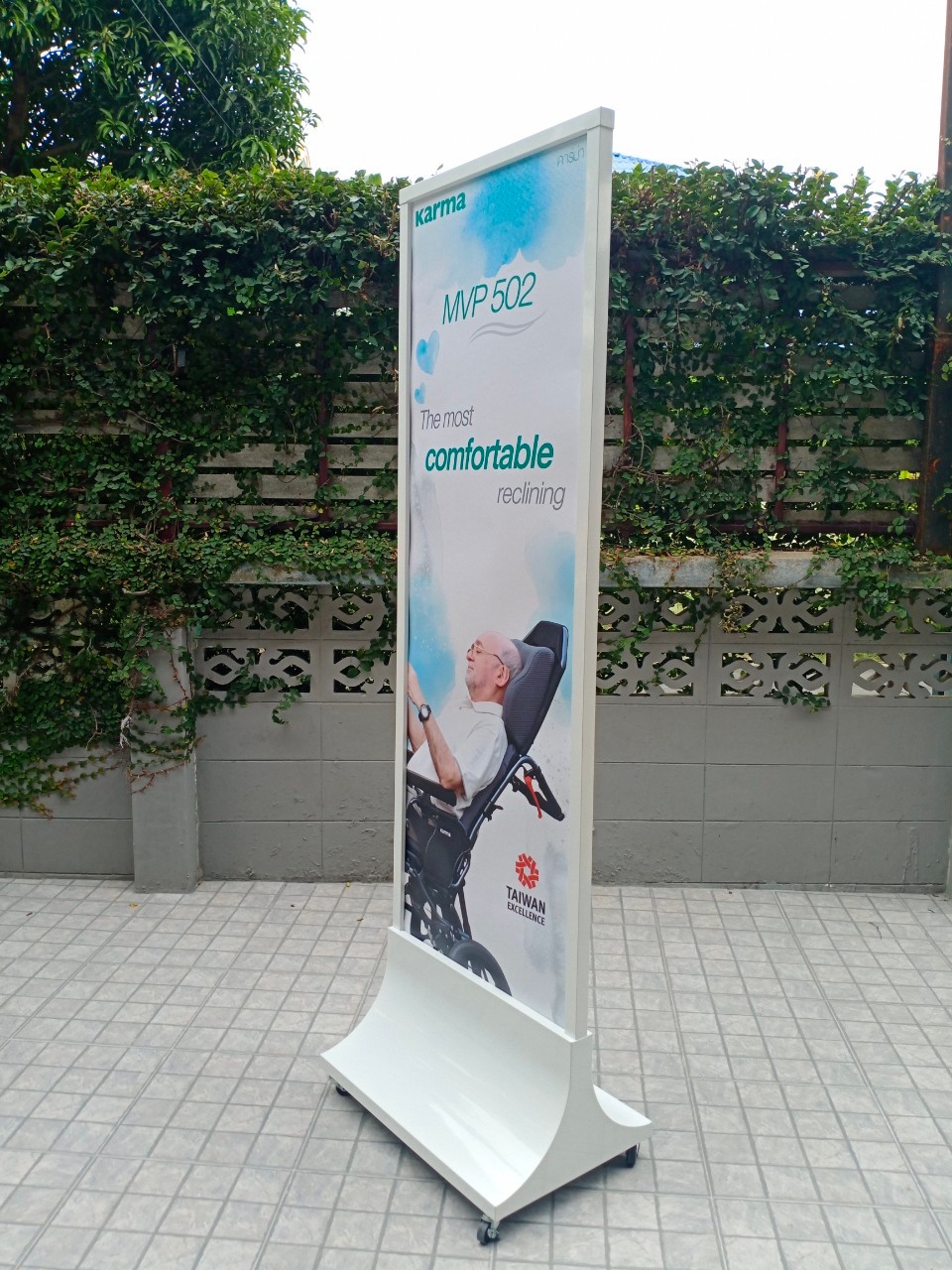 ป้ายตั้งพื้นเหล็ก สีขาว ฐานทรงสามเหลี่ยมโค้ง พร้อมล้อ ขนาด 60x160 ซม. โชว์งานพิมพ์ได้ 2 ด้าน